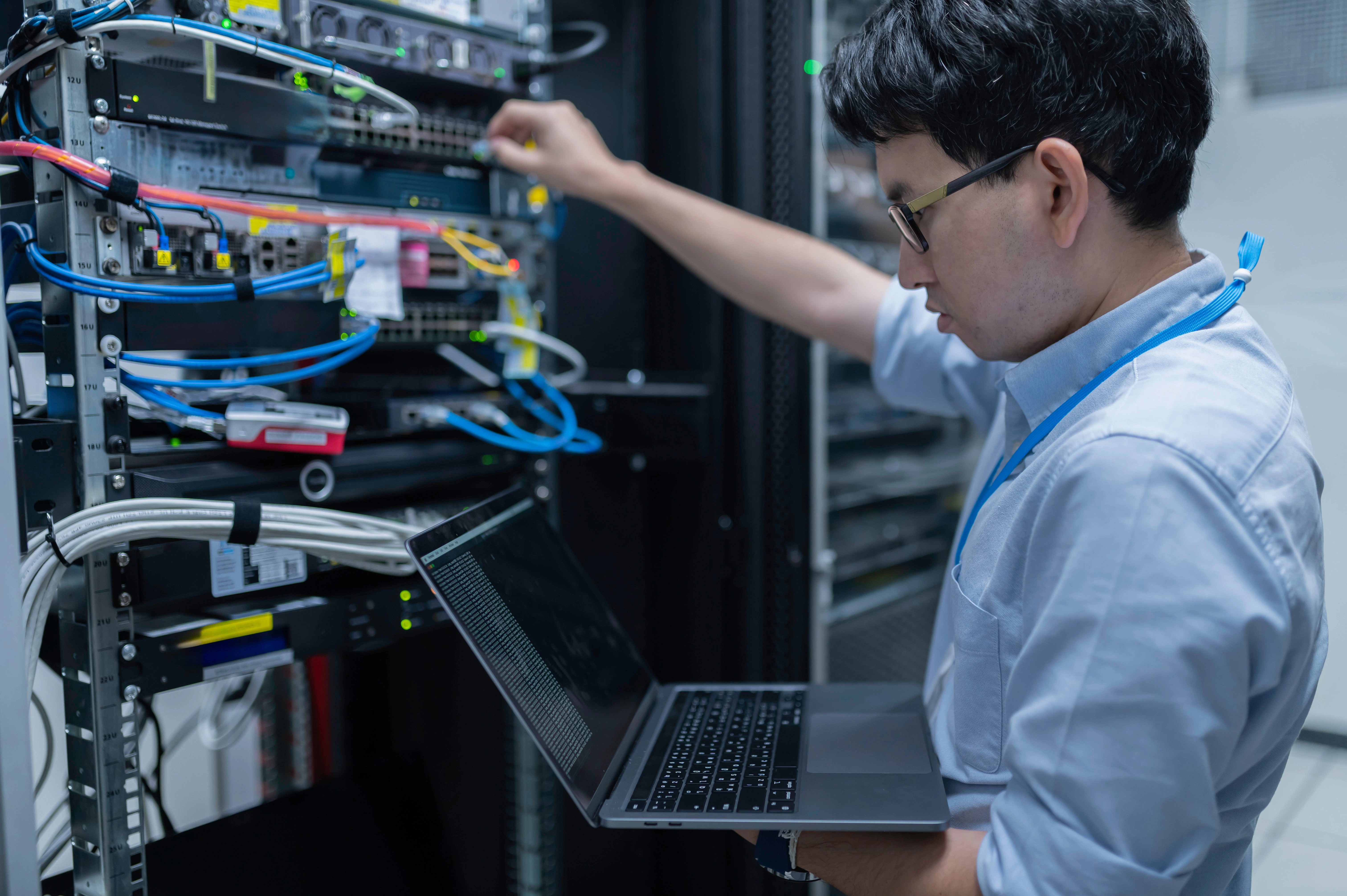Network technician servicing a server rack with a laptop, representing expert support and reliable customer service.